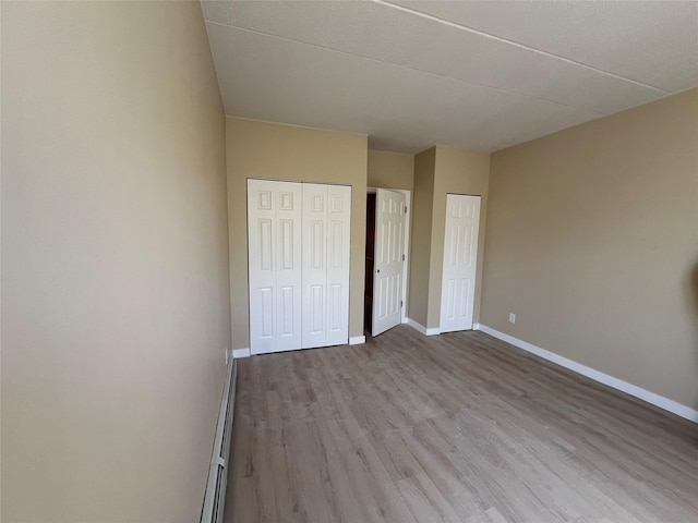 776 Brook Ave Unit 33C, Bronx, NY 10451 - unfurnished bedroom with a baseboard heating unit, wood finished floors, and baseboards