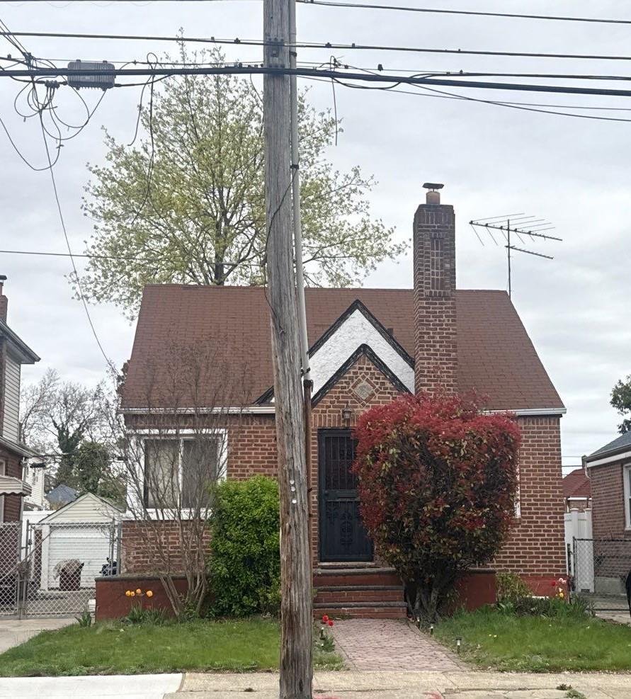 223-15 114th Rd, Cambria Heights, NY 11411 - view of front facade featuring brick siding, fence, and a chimney
