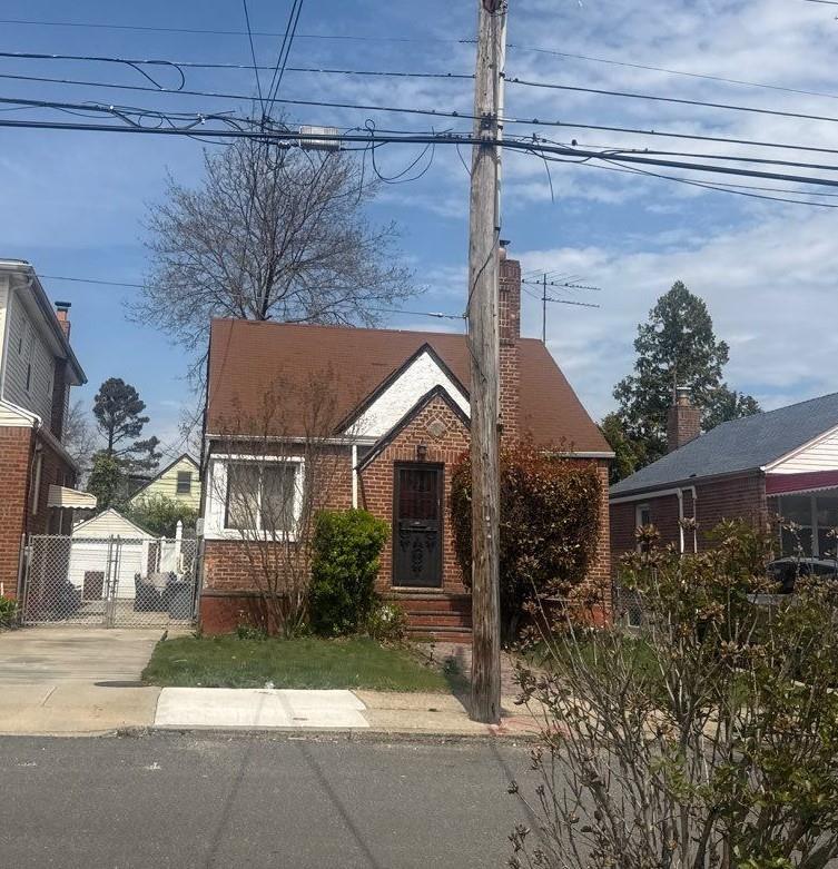 223-15 114th Rd, Cambria Heights, NY 11411 - bungalow with brick siding, fence, and a chimney