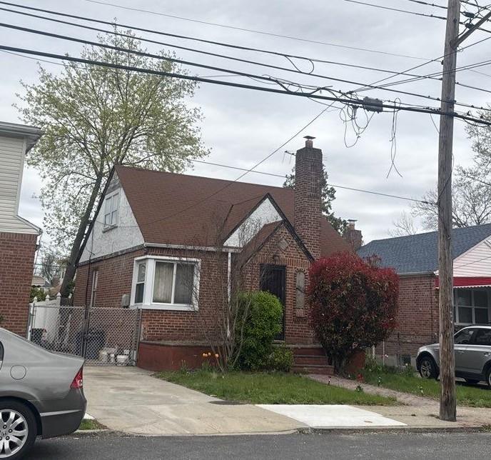223-15 114th Rd, Cambria Heights, NY 11411 - tudor-style house featuring a chimney and brick siding