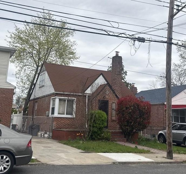 223-15 114th Rd, Cambria Heights, NY 11411 - tudor-style house featuring a chimney and brick siding