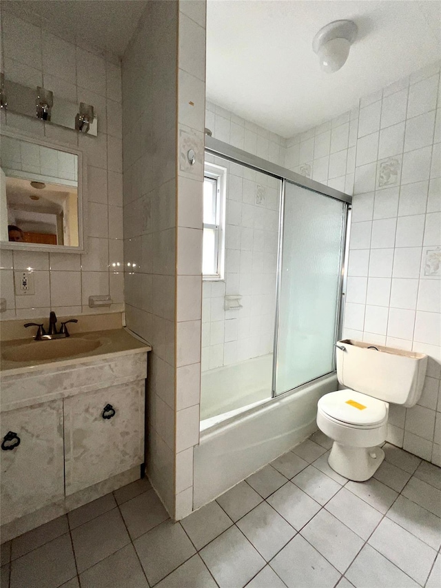 full bathroom with tile patterned flooring, enclosed tub / shower combo, toilet, and tile walls