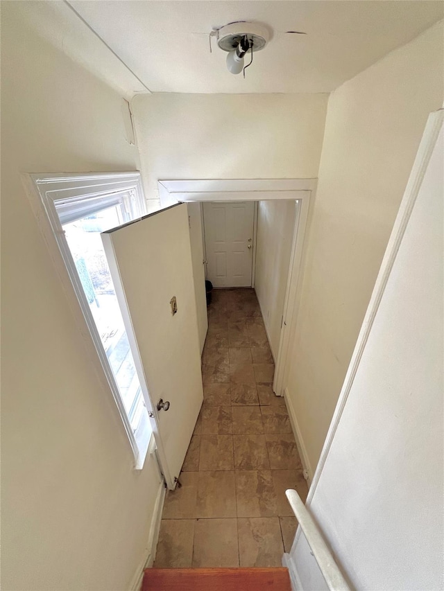 hall with baseboards and light tile patterned floors
