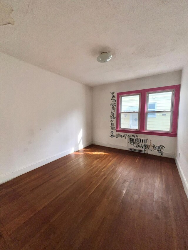 unfurnished room featuring a textured ceiling, baseboards, and wood finished floors