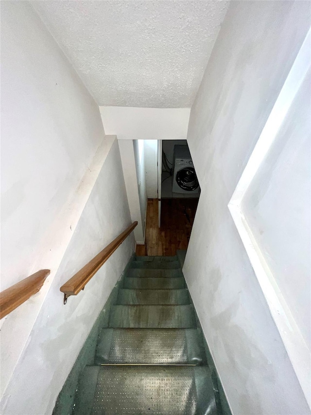 stairway featuring a textured ceiling