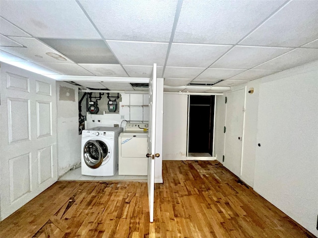 clothes washing area featuring laundry area, wood finished floors, and washer and dryer