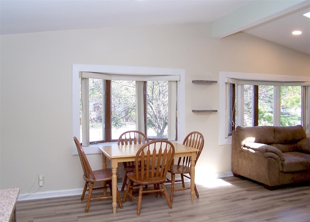 dining area with baseboards, a healthy amount of sunlight, vaulted ceiling with beams, and light wood-style floors