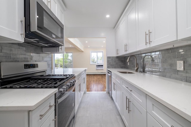 kitchen with tasteful backsplash, a sink, white cabinets, stainless steel appliances, and recessed lighting