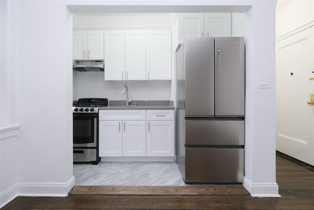 kitchen with a sink, under cabinet range hood, white cabinets, baseboards, and appliances with stainless steel finishes