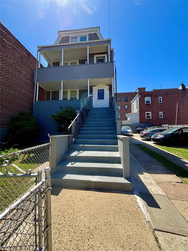 1058 Burke Ave, Bronx, NY 10469 - view of front of property with covered porch, brick siding, fence, and stairs