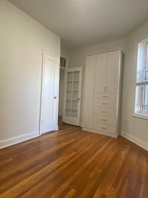 128 W 138th St Unit 5F, New York Manhattan, NY 10030 - unfurnished bedroom featuring a closet, wood finished floors, and baseboards