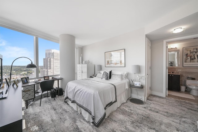 bedroom featuring baseboards, a city view, wood finished floors, and connected bathroom