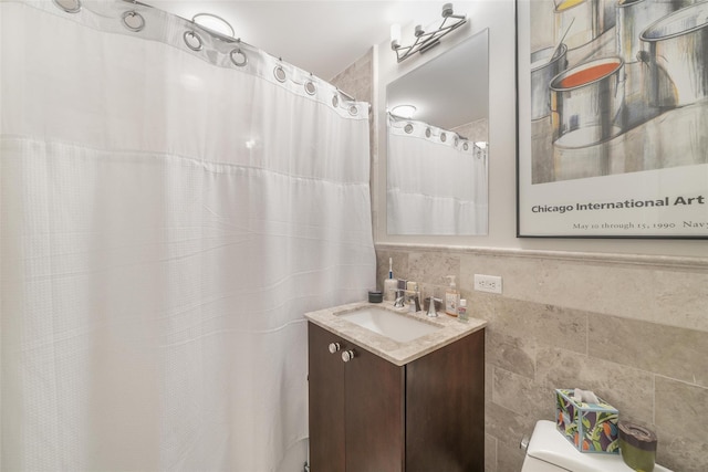 bathroom featuring toilet, tile walls, and vanity