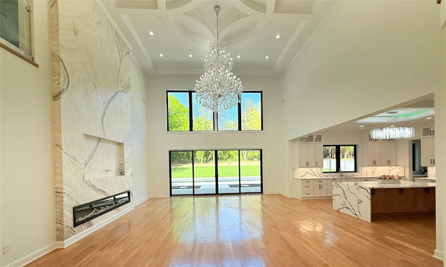 412 Mill River Rd, Oyster Bay, NY 11771 - unfurnished living room with an inviting chandelier, ornamental molding, a high ceiling, a sink, and light wood finished floors
