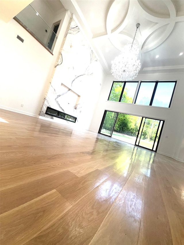 412 Mill River Rd, Oyster Bay, NY 11771 - unfurnished living room featuring an inviting chandelier, visible vents, a towering ceiling, hardwood / wood-style flooring, and coffered ceiling
