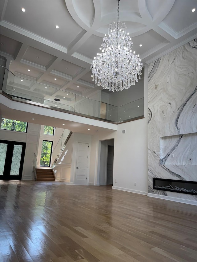 412 Mill River Rd, Oyster Bay, NY 11771 - unfurnished living room with wood finished floors, an inviting chandelier, a high ceiling, coffered ceiling, and stairs