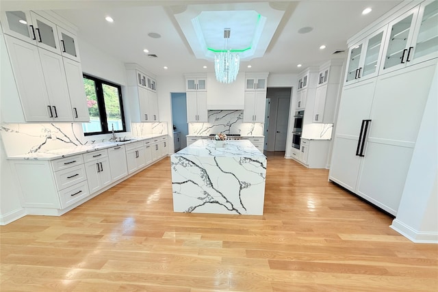412 Mill River Rd, Oyster Bay, NY 11771 - kitchen featuring decorative backsplash, a kitchen island, light wood-type flooring, a sink, and a notable chandelier