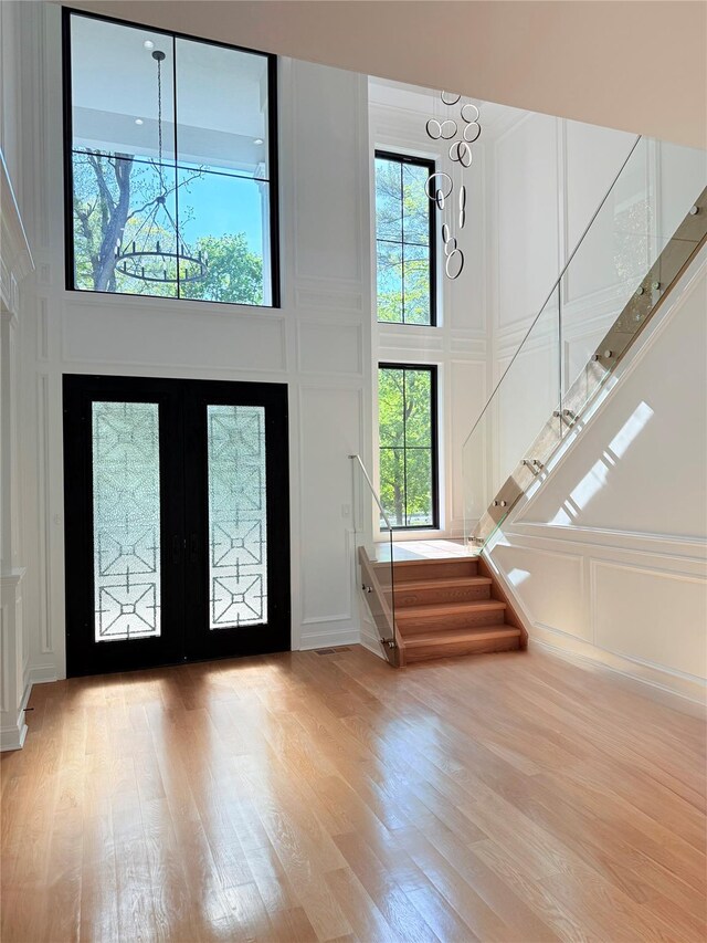 412 Mill River Rd, Oyster Bay, NY 11771 - entrance foyer featuring wood finished floors, stairway, a notable chandelier, a high ceiling, and a decorative wall