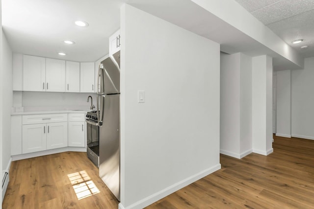57-15 69th Ln # 2, Maspeth, NY 11378 - kitchen featuring baseboards, light countertops, white cabinetry, light wood-type flooring, and recessed lighting