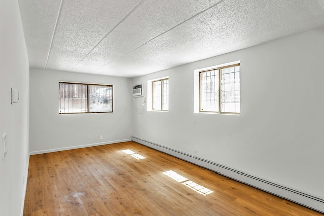 57-15 69th Ln # 2, Maspeth, NY 11378 - empty room with a baseboard radiator, a textured ceiling, wood finished floors, baseboards, and a wall mounted air conditioner
