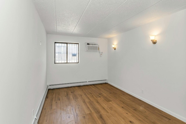 57-15 69th Ln # 2, Maspeth, NY 11378 - spare room featuring a wall unit AC, a baseboard radiator, wood finished floors, baseboards, and a textured ceiling