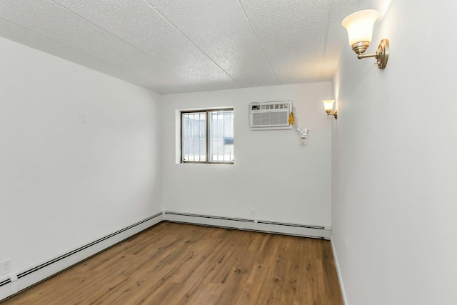 57-15 69th Ln # 2, Maspeth, NY 11378 - spare room with a wall unit AC, wood finished floors, baseboard heating, and a textured ceiling