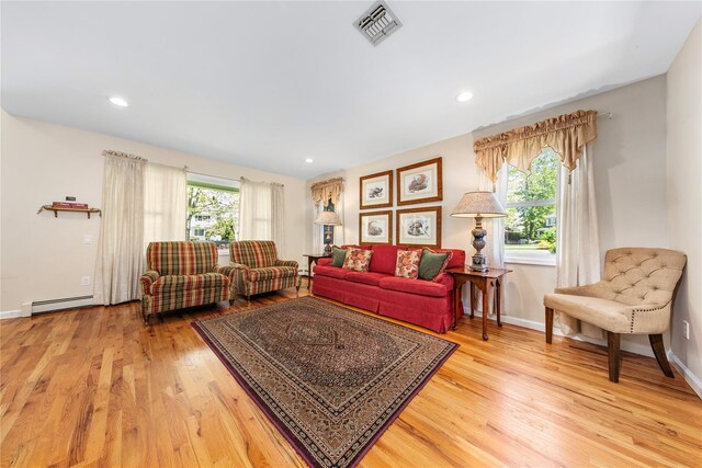 living area with a baseboard heating unit, wood finished floors, baseboards, and recessed lighting