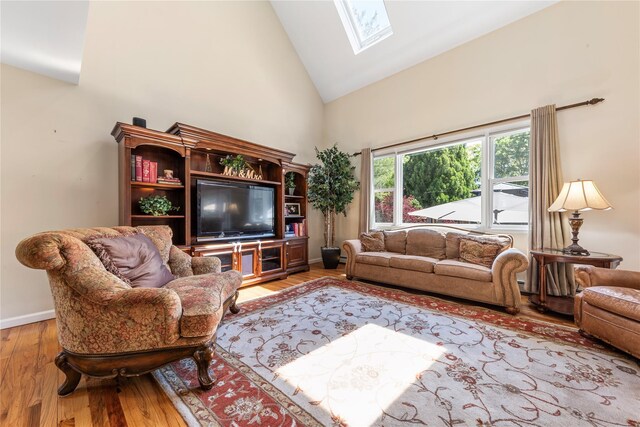 living area featuring a skylight, wood finished floors, high vaulted ceiling, and baseboards