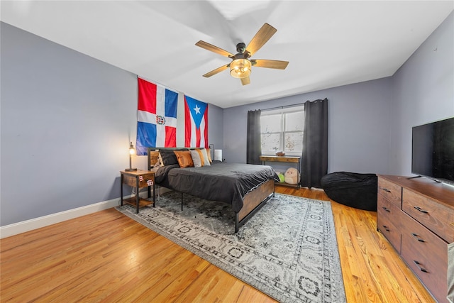 bedroom with light wood-style floors, baseboards, and a ceiling fan