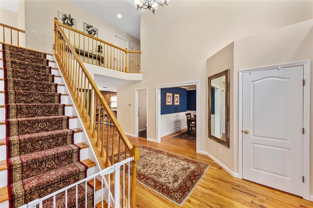 entrance foyer with stairs, light wood-style floors, recessed lighting, a wainscoted wall, and a chandelier