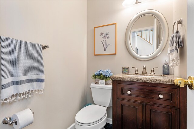 bathroom with toilet, vanity, and baseboards