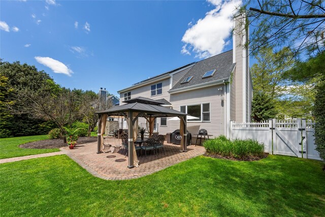 rear view of property with a gazebo, a chimney, a patio area, and a gate