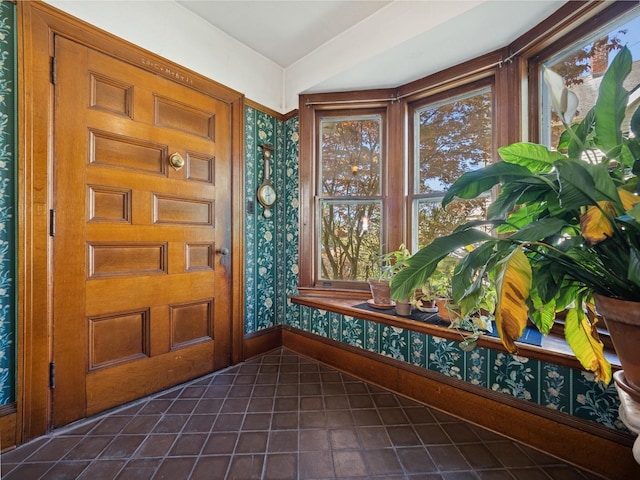 entryway featuring baseboards, dark tile patterned floors, and wallpapered walls