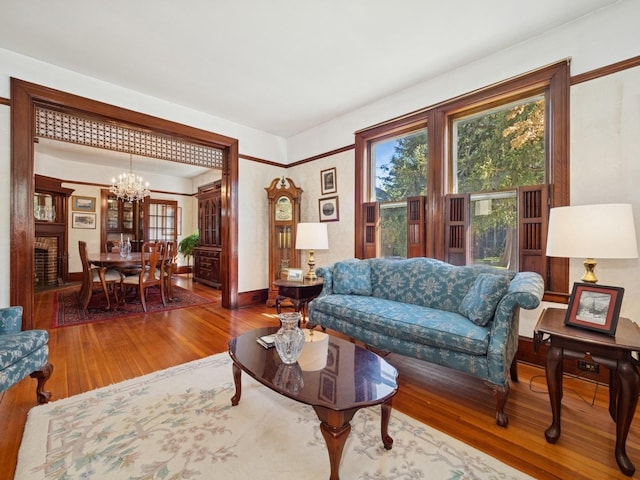 living room with baseboards, a notable chandelier, plenty of natural light, and hardwood / wood-style flooring