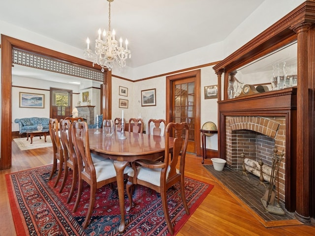dining area featuring a fireplace, wood finished floors, and a chandelier