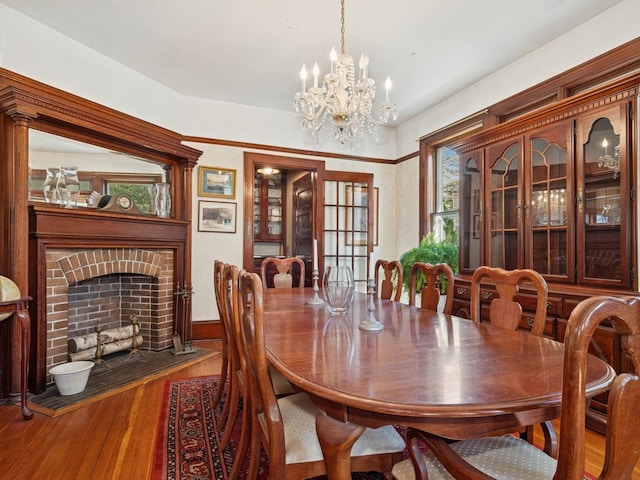 dining room featuring wood finished floors, a chandelier, and a fireplace