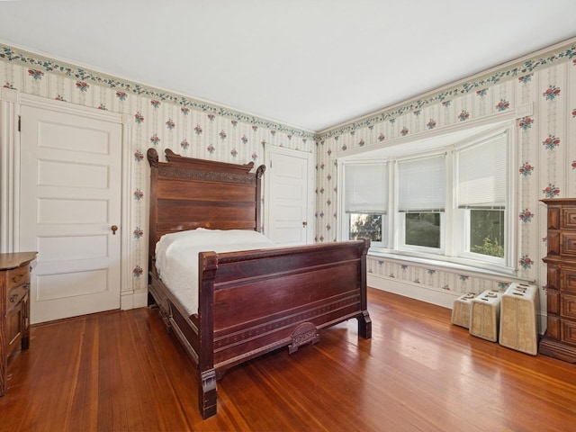 bedroom featuring wallpapered walls and dark wood finished floors