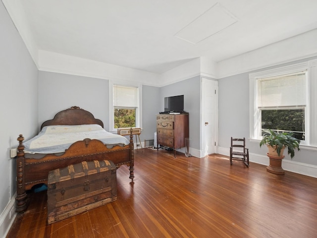 bedroom featuring baseboards, attic access, and wood finished floors