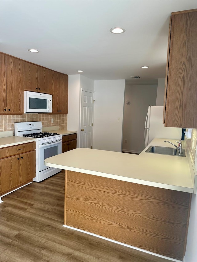 1403 Pebble Beach Path, Riverhead, NY 11901 - kitchen with white appliances, a peninsula, a sink, dark wood-style flooring, and brown cabinets