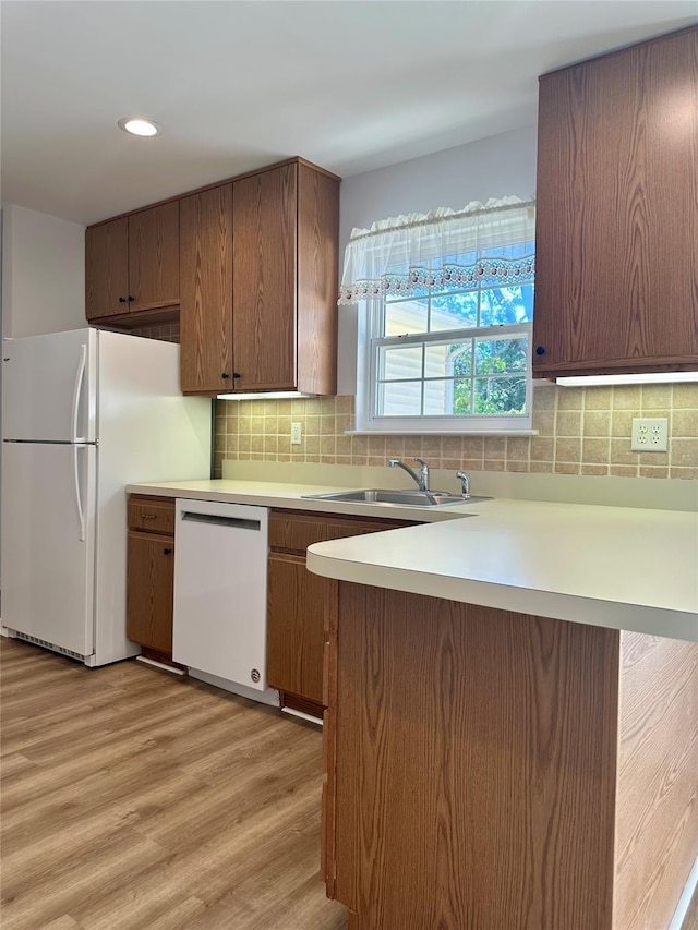 1403 Pebble Beach Path, Riverhead, NY 11901 - kitchen featuring white appliances, a sink, light countertops, light wood finished floors, and a peninsula