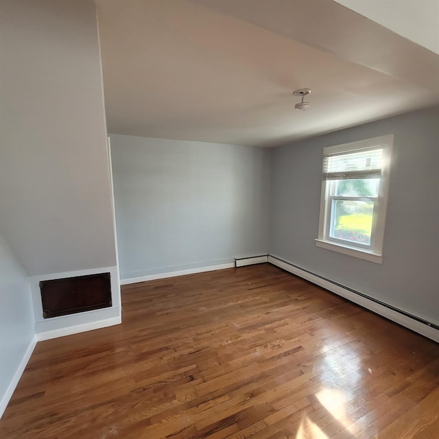 unfurnished room featuring baseboards, a baseboard heating unit, and wood finished floors