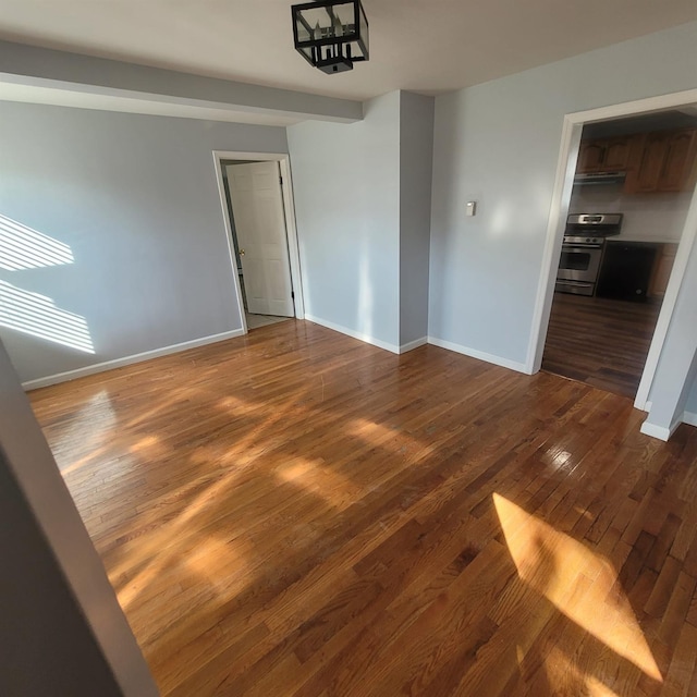unfurnished dining area with baseboards and dark wood-style flooring