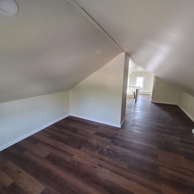 additional living space with baseboards, dark wood finished floors, and vaulted ceiling
