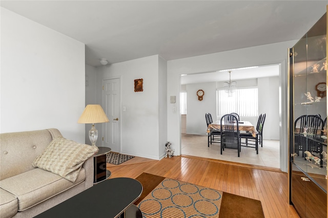 89-12 155th Ave # 1, Howard Beach, NY 11414 - living room with light wood finished floors, a chandelier, and baseboards