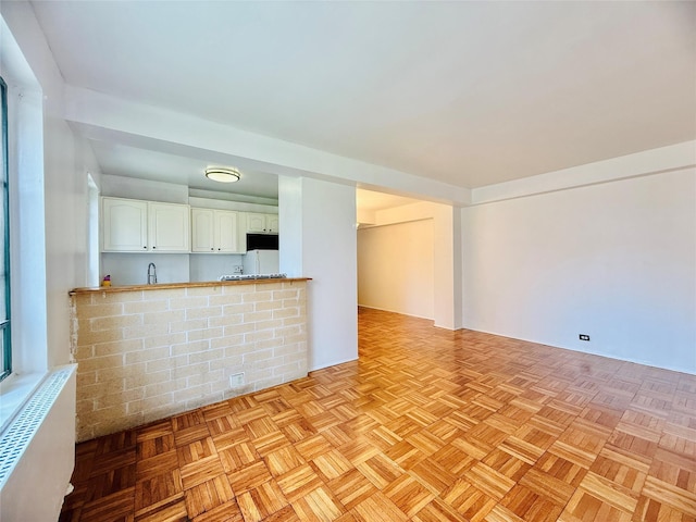 unfurnished living room featuring radiator heating unit and a sink