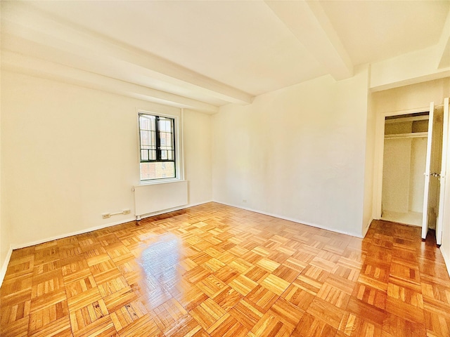 spare room with radiator heating unit, baseboards, and beamed ceiling