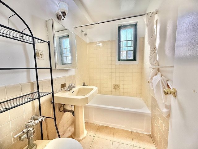 bathroom featuring a sink, toilet, tile patterned floors, shower / bath combination, and tile walls