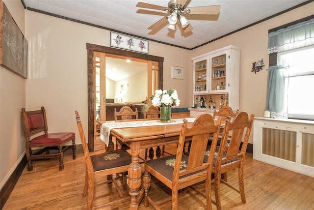 dining area with light wood finished floors, ceiling fan, crown molding, and baseboards