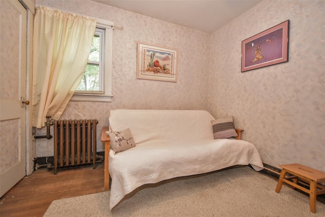 bedroom with radiator heating unit, wood finished floors, and wallpapered walls