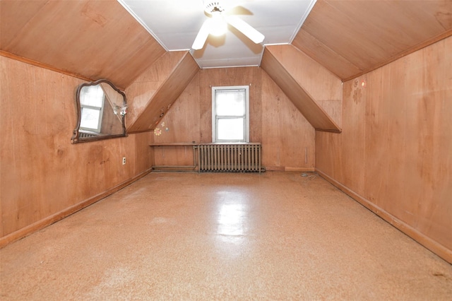 bonus room featuring radiator heating unit, wooden walls, vaulted ceiling, and a ceiling fan